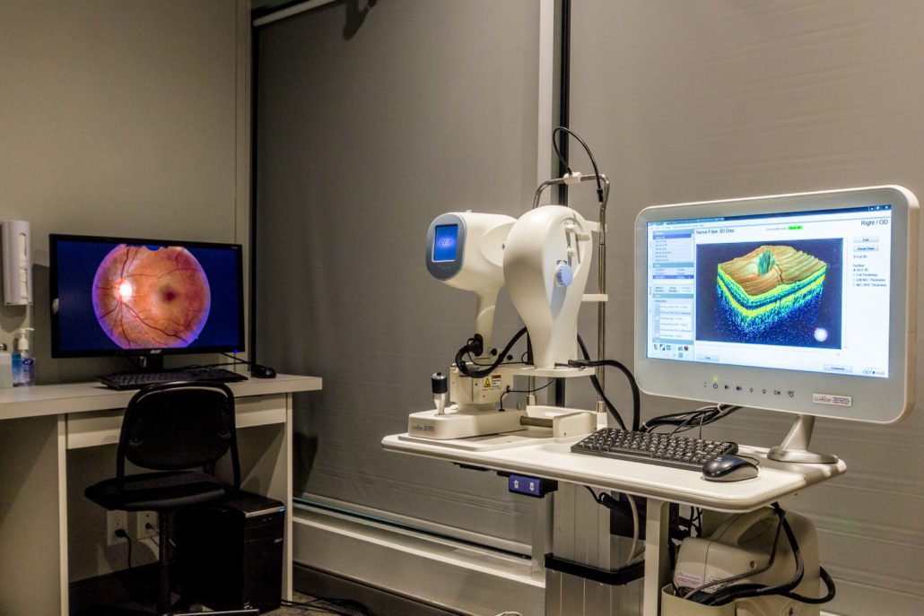 An eye exam treatment room at Mission Eye Care shows a computer with an image scan of an eye