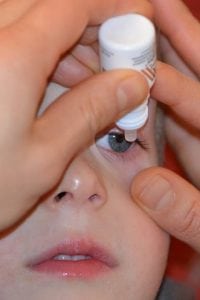 A little boy receives atropine eye drops