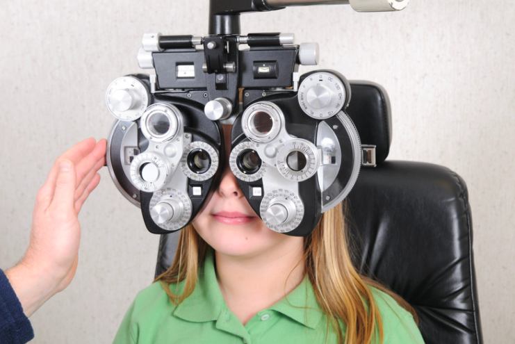A child looks into eye exam equipment to test her eyes