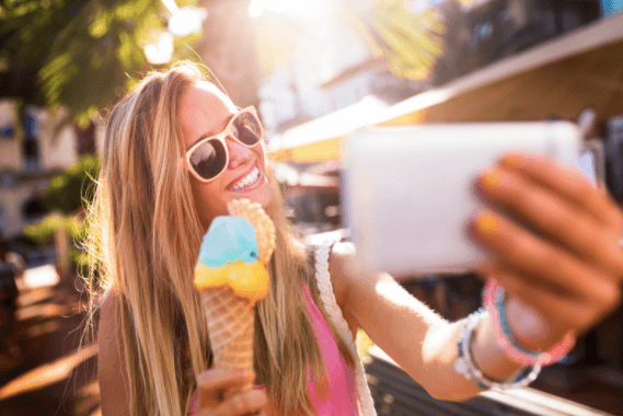 A smiling teen girl wears contact lenses and takes a selfie with ice cream