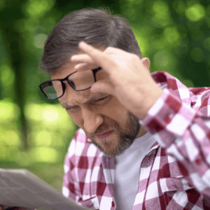 A man has myopia and needs to remove his glasses to read something